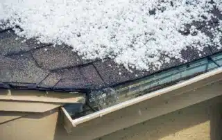 Spot five warning signs that your gutters may be damaging your roof. Hailstones on the roof and an overflowing gutter can point to clogs, poor drainage, or improper slope, all of which can lead to leaks, rot, and costly roof repairs.