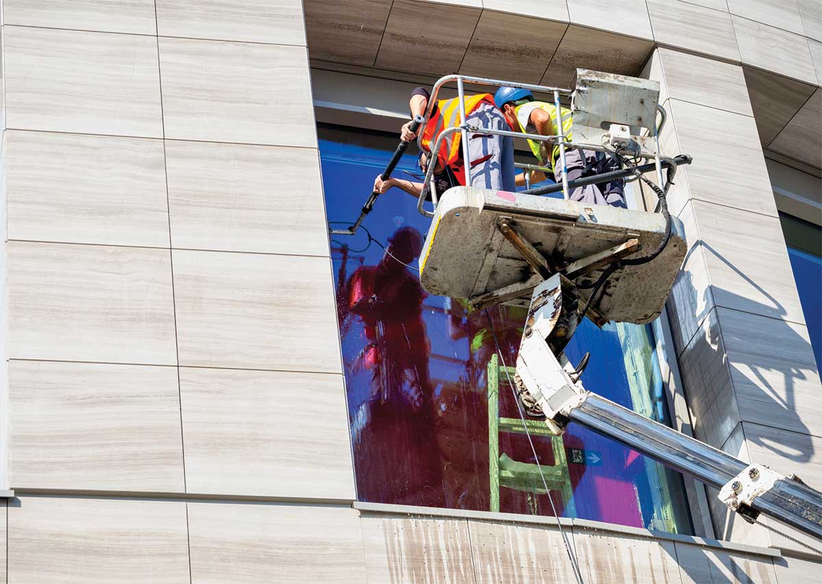 Workers cleaning glass building window - The Hidden Costs of Neglected Exterior Glass in Commercial Buildings