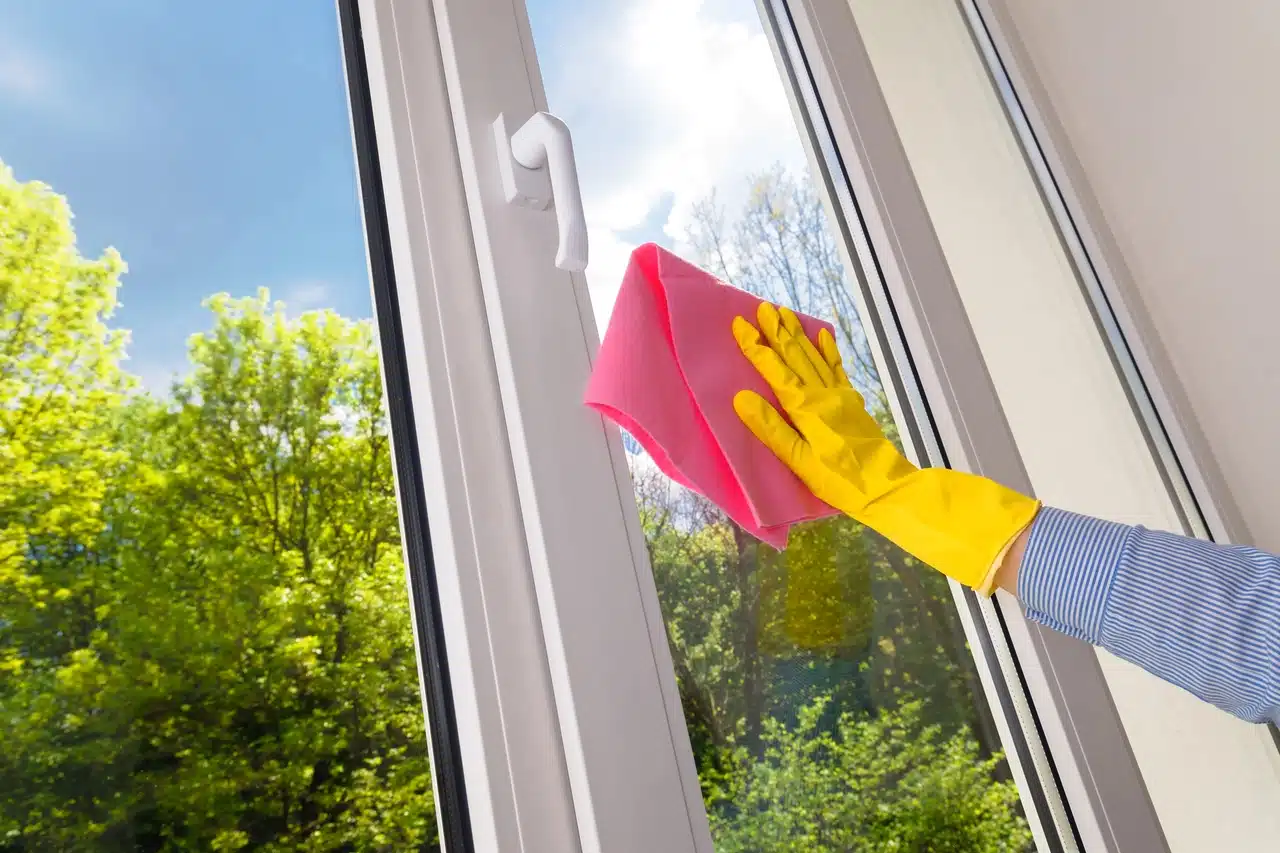 Find out why high altitude and strong UV light make Colorado windows harder to maintain. Intense sun exposure speeds up wear, fades materials, and shows grime faster. A person cleaning a window with a pink cloth and yellow gloves reflects the need for regular care.